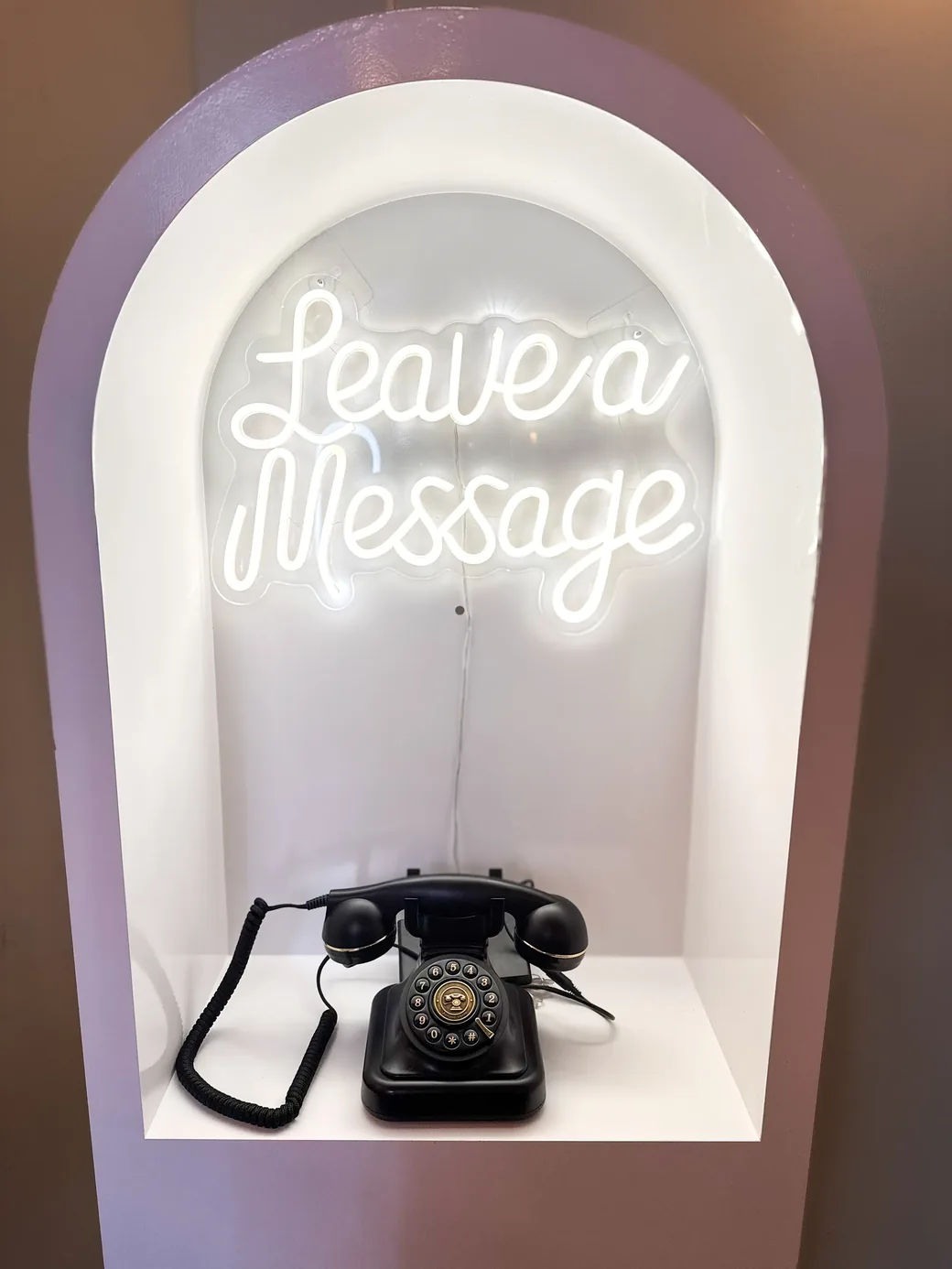 Close-up of the audio guestbook arch with glowing Leave a Message neon sign and vintage telephone