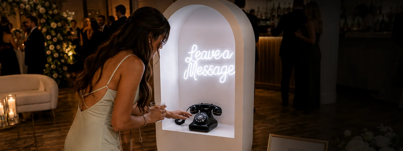 A wedding guest reaches for the vintage telephone inside the Leave a Message audio guestbook arch at a reception