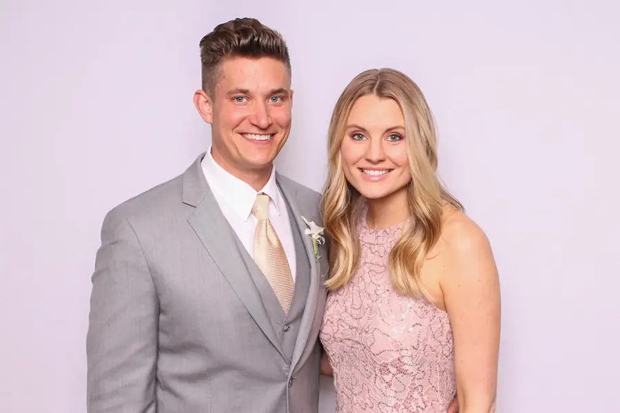 A couple posing in the photo booth against a soft neutral backdrop at their wedding