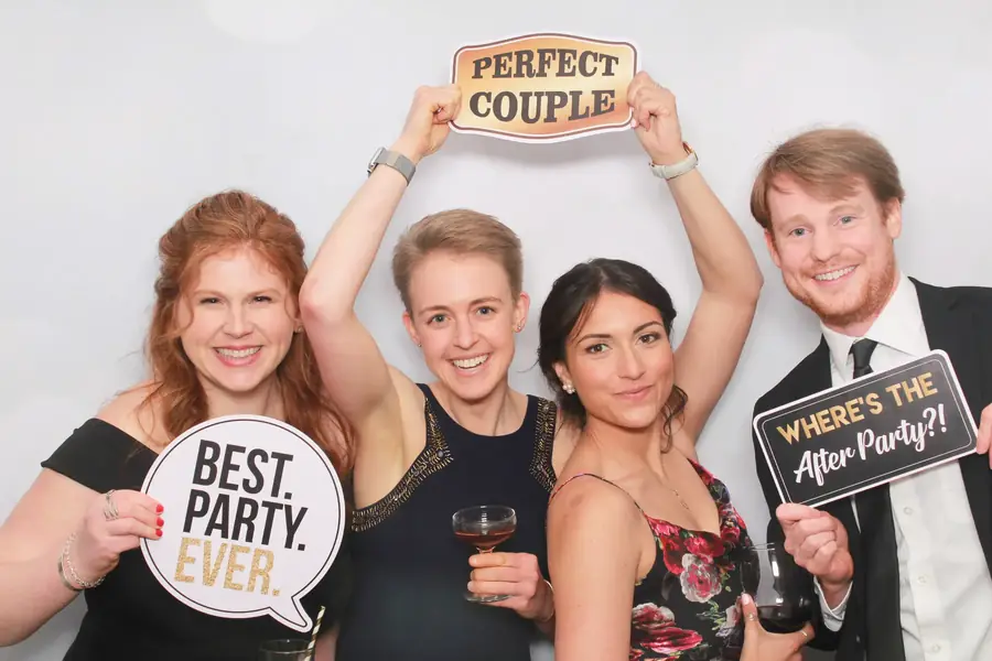 Four friends holding Best Party Ever signs in the photo booth
